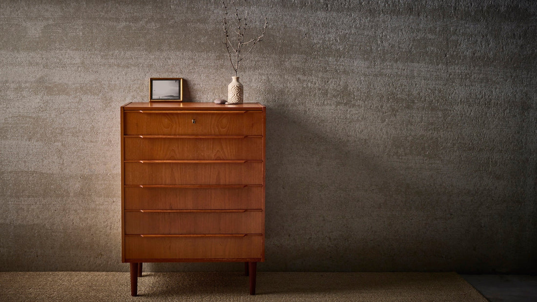 deens vintage dressoir met 6 lades, een vaas met tak en een kadertje erbpvenop