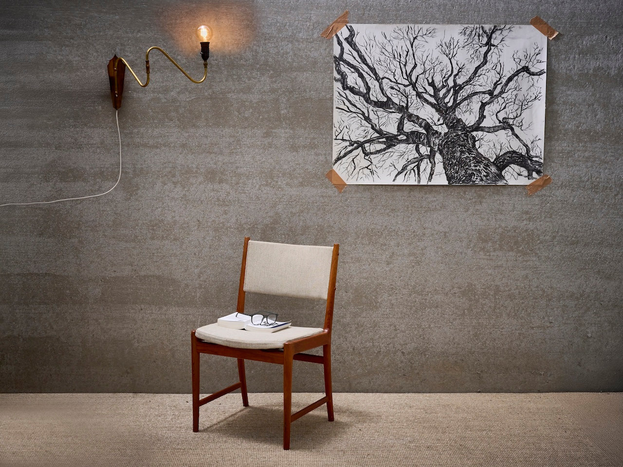 Danish vintage stoel in bruin teak hout met zitting en rugleuning uit licht gekleurde stof, wandlamp met gouden arm en houten muurplaatje, tekening met boom in houtskool
